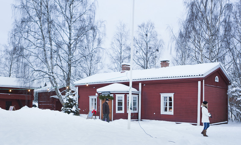 Hinttalan kotiseutumuseo talvisena päivänä, jolloin pihalla on paljon lunta, jouluvaloja sekä muutama ihminen kahvilan edustalla ulkona.