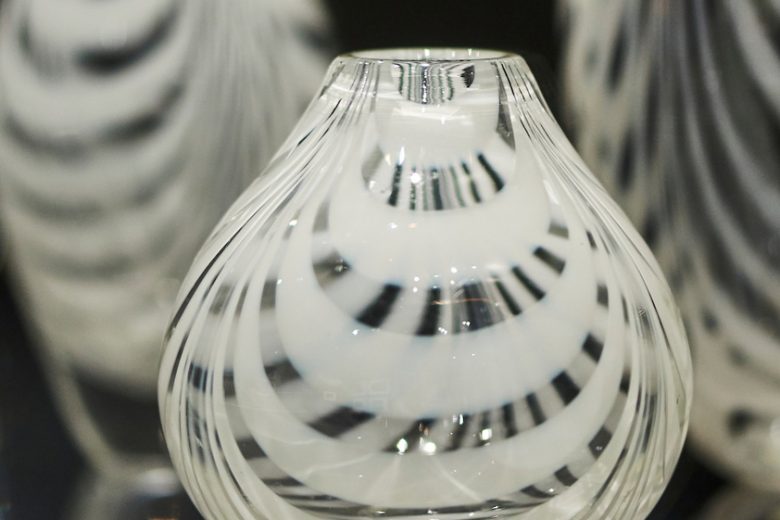 Kirkkaita lasimaljakoita, joissa on valkoisia raitoja. Maljakot ovat esillä kirjasto- ja kulttuuritalo Virran näyttelyssä.