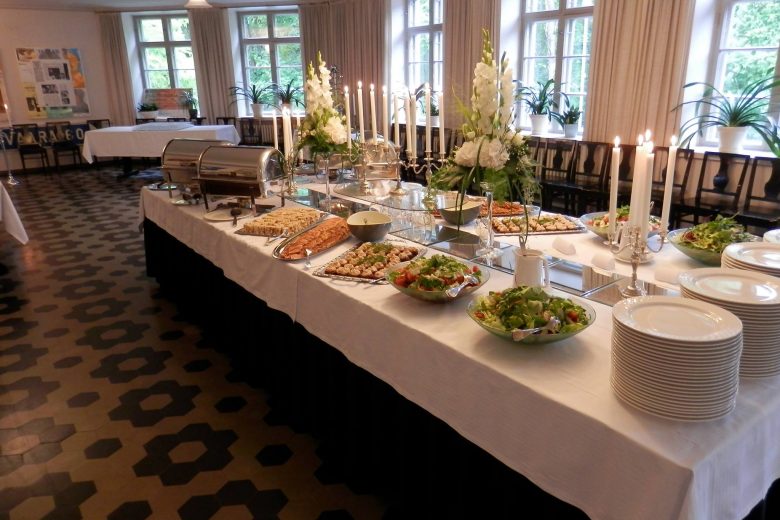 Lounas-Cateringpalvelu Kahden Kölvin kattama pitopöytä Nokian Kerholan vanhoihin tiloihin. Buffetpöydässä on esillä salaatteja, kala- ja liha-alkupaloja sekä lämpimiä ruokia teräksisissä astioissa.