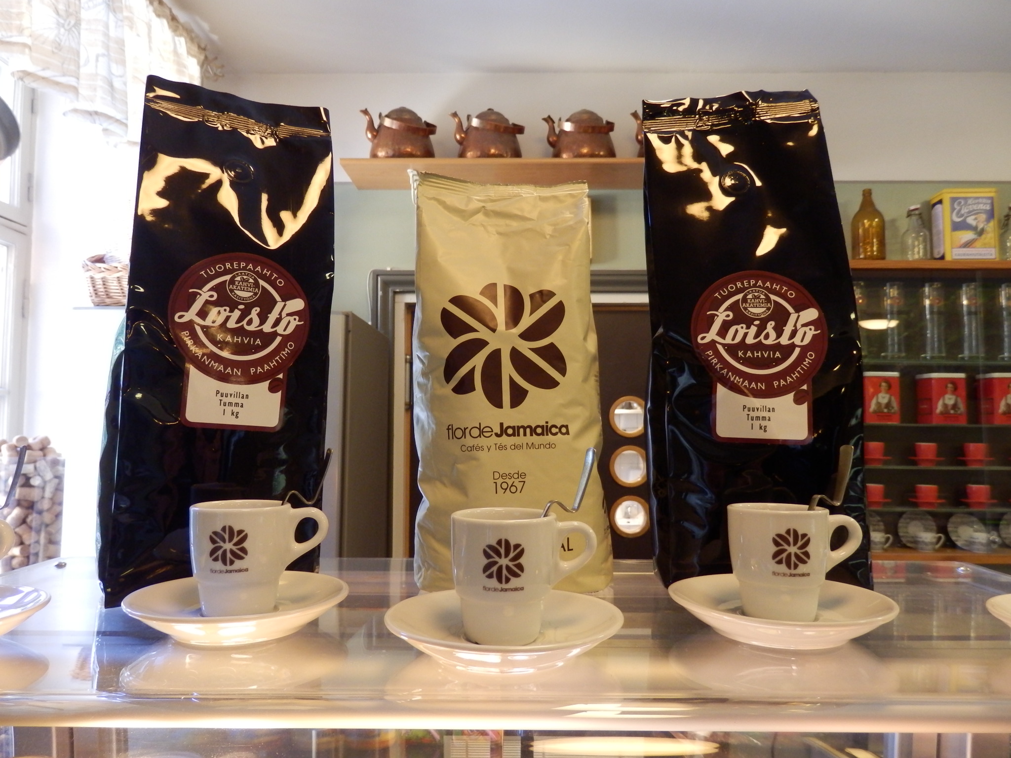 Lounas-Cateringpalvelu Kahden Kölvin kahvilatiskin päälle on koottu erilaisia tarjolla olevia kahvipapuja ja kolme pientä espressokuppia.