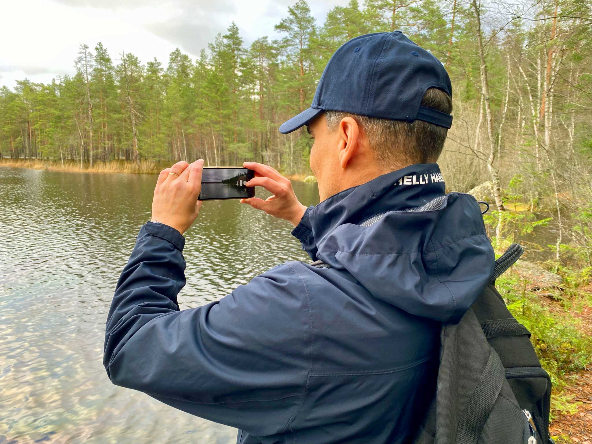 Mies kuvaa kännykkäkameralla Alisenjärven maisemia.