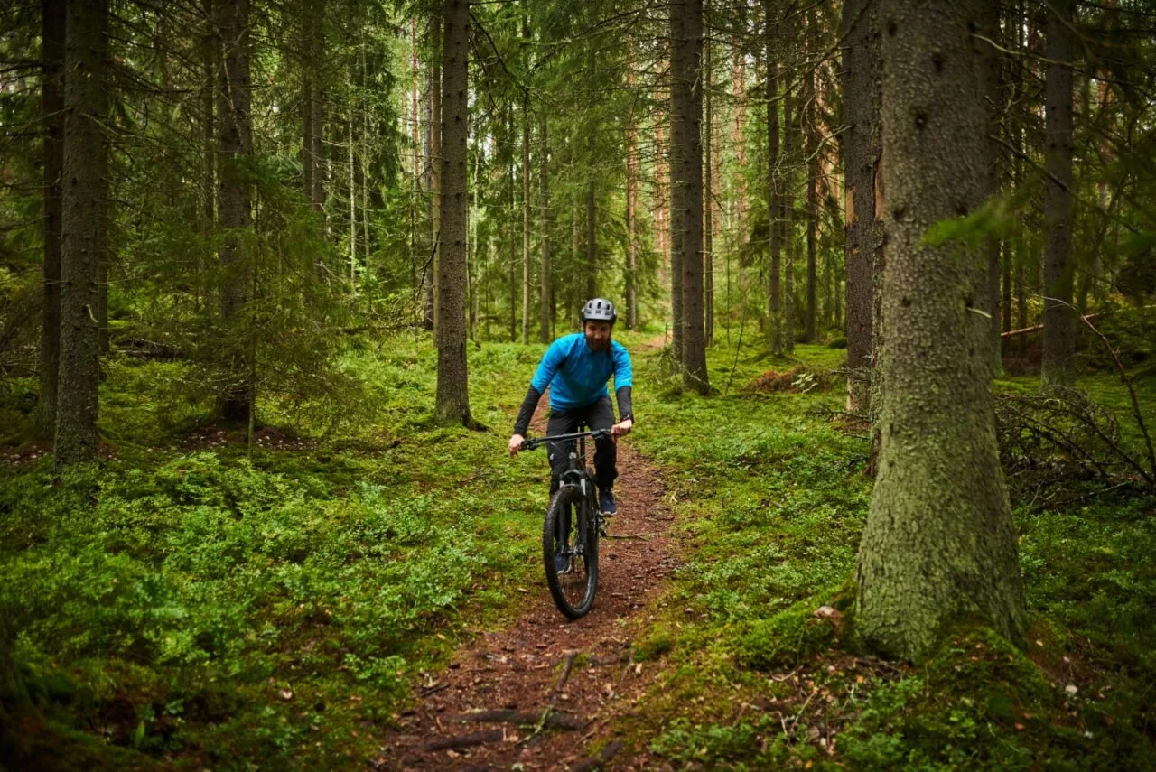 Mies ajaa maastopyörällä polkua pitkin metsässä.